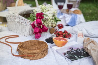 Piknik süslemeler, cannotier, kruvasan, çiçek, meyve. Yiyecek ve içecek farklı türde beyaz battaniye açık piknik öğle yemeği için devam eder. Fotoğrafı kapatın. Mutlu tatil kavramı. Mutlu anneler günü.