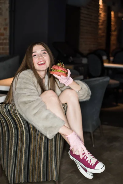 beautiful, sexy girl eating a burger. Concept. weight loss. Pink vegetarian burger. Fashion advertising concept. Casual swag style.