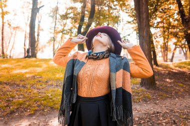 Sezon ve insanlar kavramı - güzel mutlu genç kız eğleniyor yaprakları ile sonbahar parkta. Gülen kız. Sonbahar hava. Güneş ışınları model arkadan aydınlatmak.