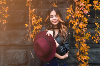 Genç kadın rahat kıyafetler ve siyah deri ceket kentsel şehir arka plan sonbahar portre üzerinde moda. Hippi kız Sokağı'nda poz. Zarif sonbahar giysileri moda uzun saç modeli. vintade şapka.