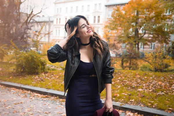 Young fashion woman in casual clothes and black leather jacket over urban city background autumn portrait. Hipster girl posing at street. Fashionable long hair model in elegant autumn clothes. vintade hat.