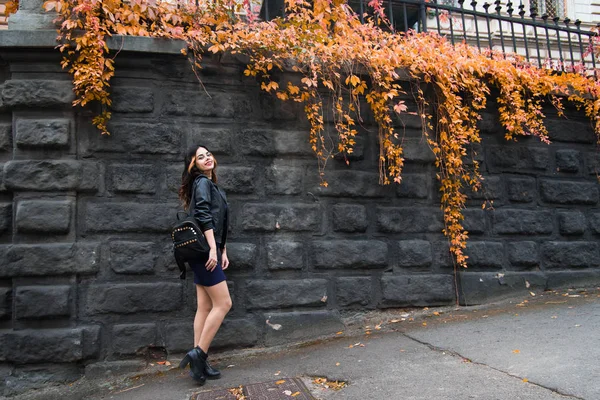 Young fashion woman in casual clothes and black leather jacket over urban city background autumn portrait. Hipster girl posing at street. Fashionable long hair model in elegant autumn clothes. vintade hat.