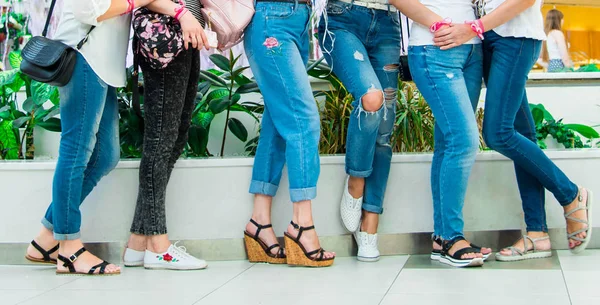 Women near the wall in jeans and t-shirts. Women\'s party before the wedding. Girls with flowers and pink white ribbons on their hands.