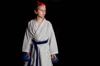 Genç çocuk eğitim karate siyah arka plan üzerine. Mavi kemer ve eldiveni, karate eldiven. Sevimli genç duyguları çocuk eğitim. Şok el ve çığlık.