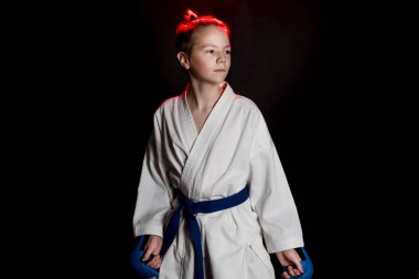 Genç çocuk eğitim karate siyah arka plan üzerine. Mavi kemer ve eldiveni, karate eldiven. Sevimli genç duyguları çocuk eğitim. Şok el ve çığlık.