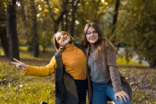 二十代の少女は 秋服で楽しんでいます ドライを投げて面白いガール フレンドは 秋に市内の葉します 秋の散歩に幸せな家族 Geasture — ストック写真