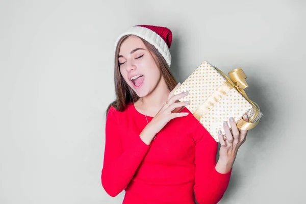 Smiling teenage girl in santa helper hat with many gift boxes on white background. Positive emotional Santa girl. Concept of selling and Christmas shopping. Xmas. Girl hugging gifts.