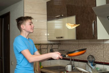 O gösterir gibi sevimli duygular genç çocuk krep atarak. Evde yemek pişirmek.