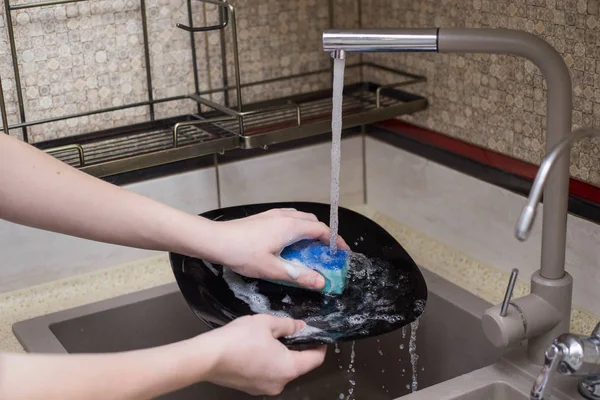 Çocuk lavaboda bulaşıkları yıkıyor.