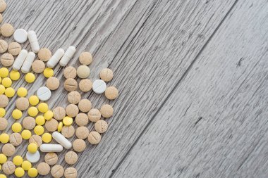 Ahşap arka planda tedavi ve sağlık hizmetleri için tıbbi renkli haplar, kapsüller veya takviyeler.