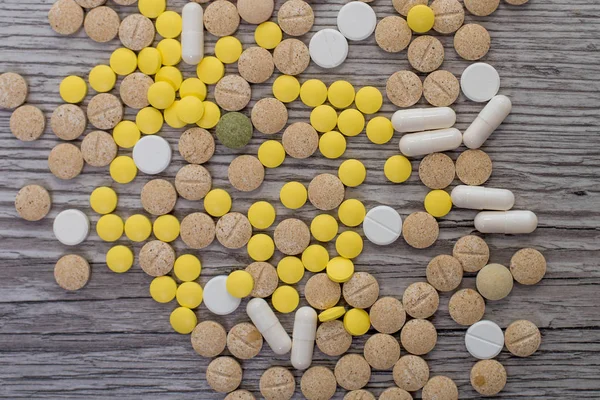 Orvosi színes tabletták, kapszulák vagy kiegészítők a kezelés és az egészségügyi ellátás fából készült háttér. — Stock Fotó