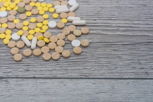 Pillole colorate mediche, capsule o integratori per il trattamento e l'assistenza sanitaria su sfondo di legno. — Foto Stock