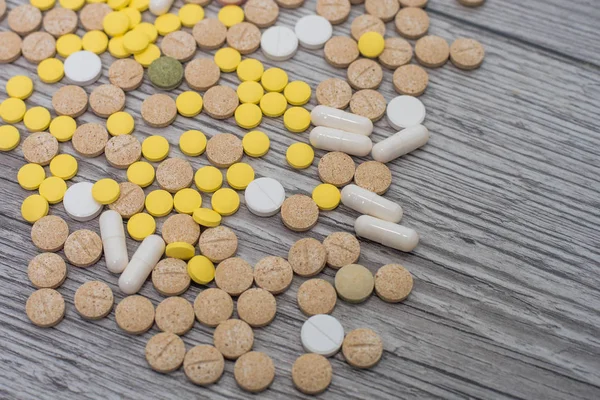 Pillole colorate mediche, capsule o integratori per il trattamento e l'assistenza sanitaria su sfondo di legno. — Foto Stock