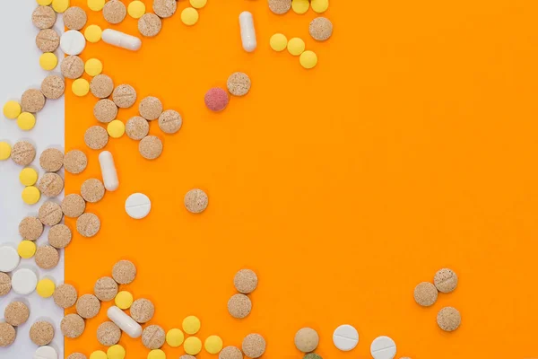 Pillole colorate mediche, capsule o integratori per il trattamento e l'assistenza sanitaria su sfondo arancione e bianco. Idea creativa. Droga. Triste. Muori. Malattia . — Foto Stock