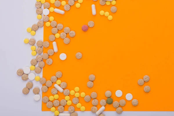 Pillole colorate mediche, capsule o integratori per il trattamento e l'assistenza sanitaria su sfondo arancione e bianco. Idea creativa. Droga. Triste. Muori. Malattia . — Foto Stock