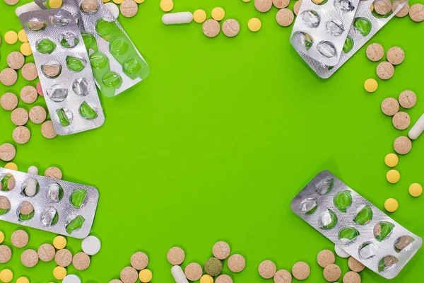 Pillole colorate mediche, capsule o integratori per il trattamento e l'assistenza sanitaria su sfondo verde. Idea creativa. Droga. Triste. Muori. Malattia . — Foto Stock