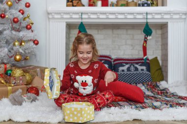 Mutlu Noeller ve mutlu tatiller! Şirin küçük kız içeride Noel ağacını süslüyor. Mutlu, küçük, gülümseyen kız Noel hediyesi kutusuyla.