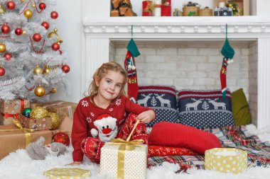 Mutlu Noeller ve mutlu tatiller! Şirin küçük kız içeride Noel ağacını süslüyor. Mutlu, küçük, gülümseyen kız Noel hediyesi kutusuyla.