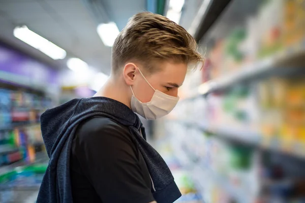 Boy wears protected mask in store. Shopping time during coronavirus outbreak.Boy in a medical mask. Quarantine and protection virus, flu, epidemic COVID-19. Coronavirus quarantine.
