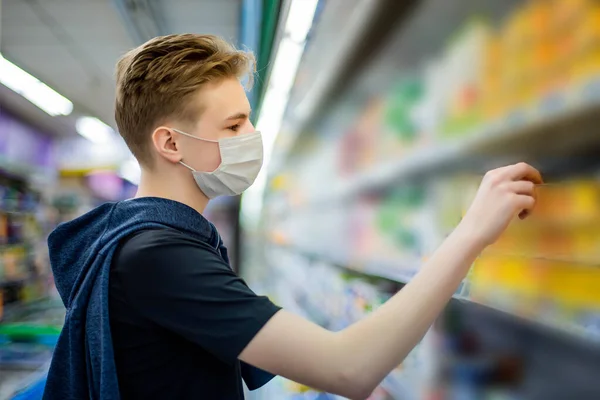 Boy wears protected mask in store. Shopping time during coronavirus outbreak.Boy in a medical mask. Quarantine and protection virus, flu, epidemic COVID-19. Coronavirus quarantine.