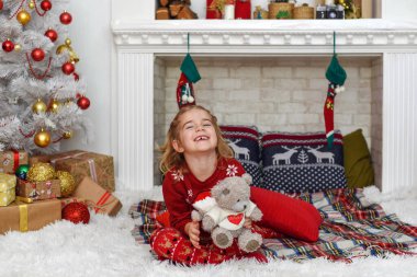 Mutlu Noeller ve mutlu tatiller! Şirin küçük kız içeride Noel ağacını süslüyor. Mutlu, küçük, gülümseyen kız Noel hediyesi kutusuyla.