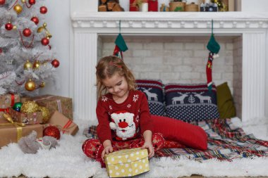 Mutlu Noeller ve mutlu tatiller! Şirin küçük kız içeride Noel ağacını süslüyor. Mutlu, küçük, gülümseyen kız Noel hediyesi kutusuyla.