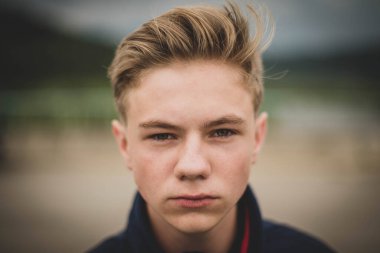 Gençlik çağında yakışıklı bir çocuk, güzel bir sonbahar arkaplanındaki mutsuz, üzgün portreyi kapatır.