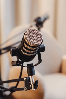 Mikrofon, iyi ışıklandırılmış bir röportaj alanında, canlı podcast tartışmaları için hazır bekliyor. Çekici konuşmaları yakalamak için bir kamera konumlandırıldı.