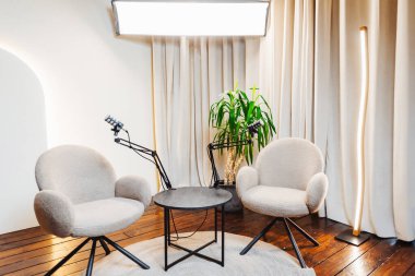 İyi tasarlanmış bir podcast ropörtaj alanı gösterileri iki rahat sandalye, monte mikrofonlar ve yumuşak ışıklandırma anlamlı sohbetler için davetkar bir ortam yaratıyor..