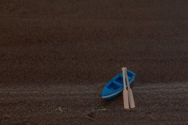 Mavi ahşap tekne kıyıda küreklerle duruyor.