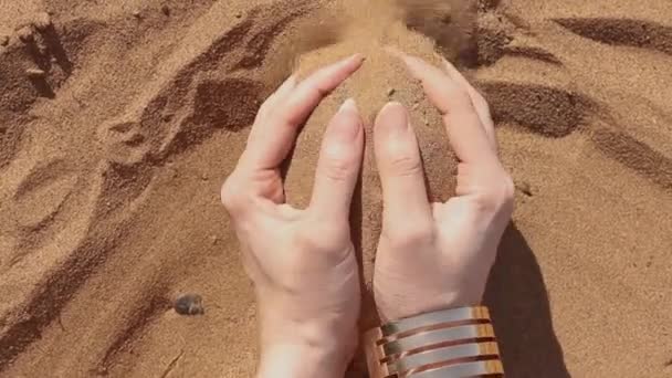 I grani di sabbia scorrono tra le mani delle donne. Donna che tiene e libera la sabbia attraverso le dita. Vista panoramica — Video Stock