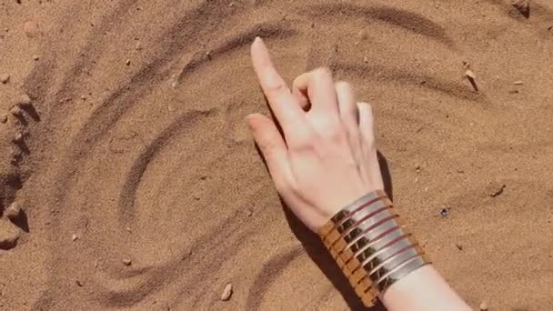 Крупный план женщины, рисовавшей сердце пальцами на песчаном пляже — стоковое видео