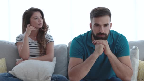 一对年轻的不幸的夫妇在他们的沙发上静静地坐着 他们的脸上带着悲伤和侮辱性的表情进行了争论和斗争 感情上的困难成了有选择的焦点 — 图库视频影像