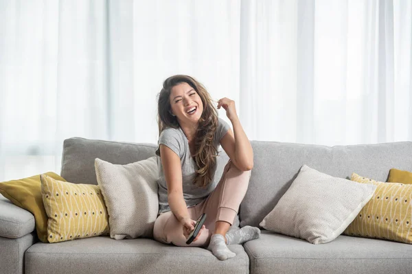 Genç ve güzel bir kız kanepede oturuyor ve boş bir öğleden sonra televizyon veya komedi dizisi seyrediyor. Yüzünde büyük bir gülümseme ve mutlu bir duygu var.