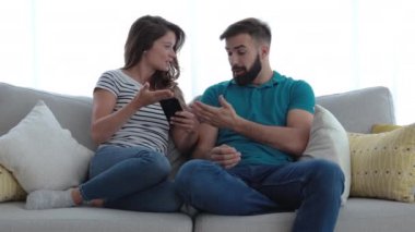 Genç çift cep telefonunda mesajlaşma konusunda tartışıyor ve adam kıskanç kız arkadaşının neden bahsettiğini bilmiyormuş gibi davranıyor.