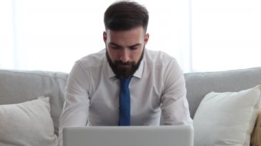 Genç, tişörtlü ve kravatlı serbest çalışan adamın dizüstü bilgisayarına bakıp olumsuz grafikler ve kriz sonrası istatistikler okuduğunu ve piyasanın çöktüğünü vurguladı.