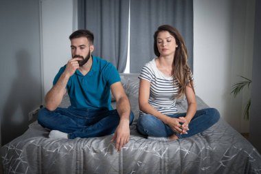 Genç adam ve kadın, erkek arkadaş ve kız arkadaş, yatakta sessizce oturuyorlar ve kavga ettikten sonra konuşmuyorlar ve yeni kıyafetlere harcadığı para hakkında tartışıyorlar.