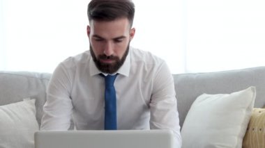 Gömlekli ve kravatlı genç serbest çalışan bir iş adamı dizüstü bilgisayarında şirket patronuna e-posta yazıyor.