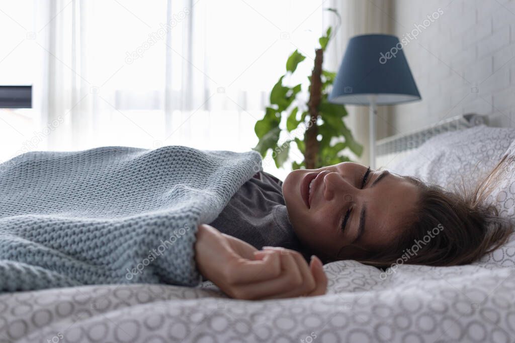 Girl lying in the bed in the morning with natural sunlight entering the room through the window