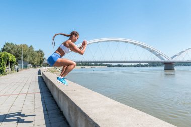 Genç, seksi, terli, formda bir kadın spor salonunda vücut egzersizi yapmak için duvarda atlıyor.