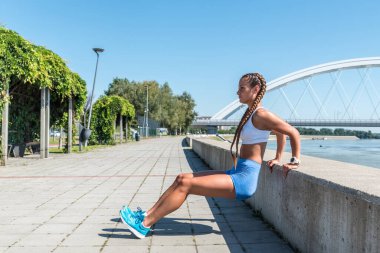 Genç seksi, kaslı, şortlu kadın vücut ağırlığı antrenmanı yaparken duvara vuruyor.