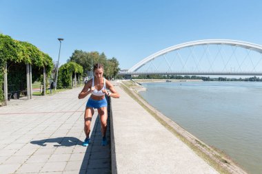 Genç seksi, terli, kaslı, formda bir kadın spor salonunda vücut egzersizi yapmak için duvardan atlıyor.