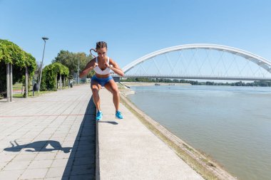Genç seksi, terli, kaslı, formda bir kadın spor salonunda vücut egzersizi yapmak için duvardan atlıyor.