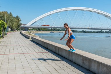 Şortlu, seksi ve formda bir kadın yüksek dizlerle atlıyor. Açık hava sert vücut egzersizi antrenmanı gibi.