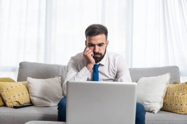 Genç, tişörtlü ve kravatlı serbest çalışan adamın dizüstü bilgisayarına bakıp olumsuz grafikler ve kriz sonrası istatistikler okuduğunu ve piyasanın çöktüğünü vurguladı.