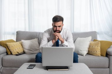 Genç, tişörtlü ve kravatlı serbest çalışan adamın dizüstü bilgisayarına bakıp olumsuz grafikler ve kriz sonrası istatistikler okuduğunu ve piyasanın çöktüğünü vurguladı.