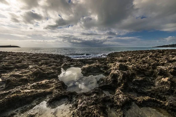 Sunset over the sea with rocks and cloudy sky