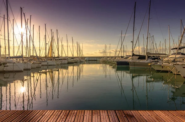 Yürüme yolu ve gün batımında tekneleri olan bir Marina.