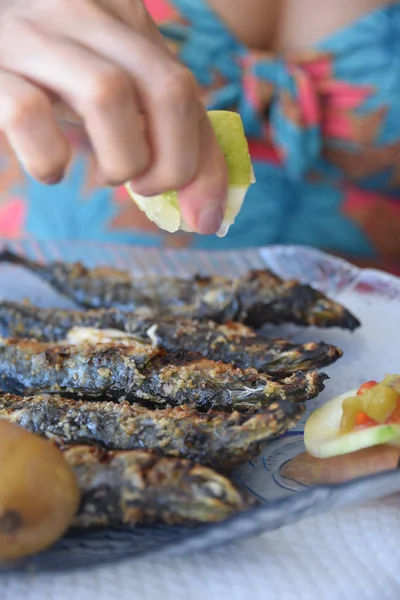 Lisbona, Portogallo: Una tavola calda spreme succo di limone sul pesce appena grigliato — Foto Stock