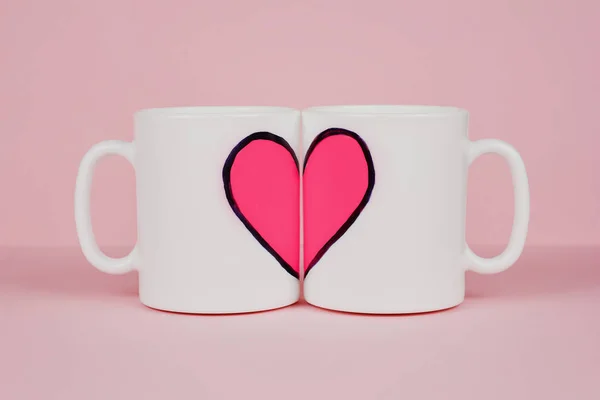 Pink heart and two white cups on pink background. Valentine's day, love, wedding concept